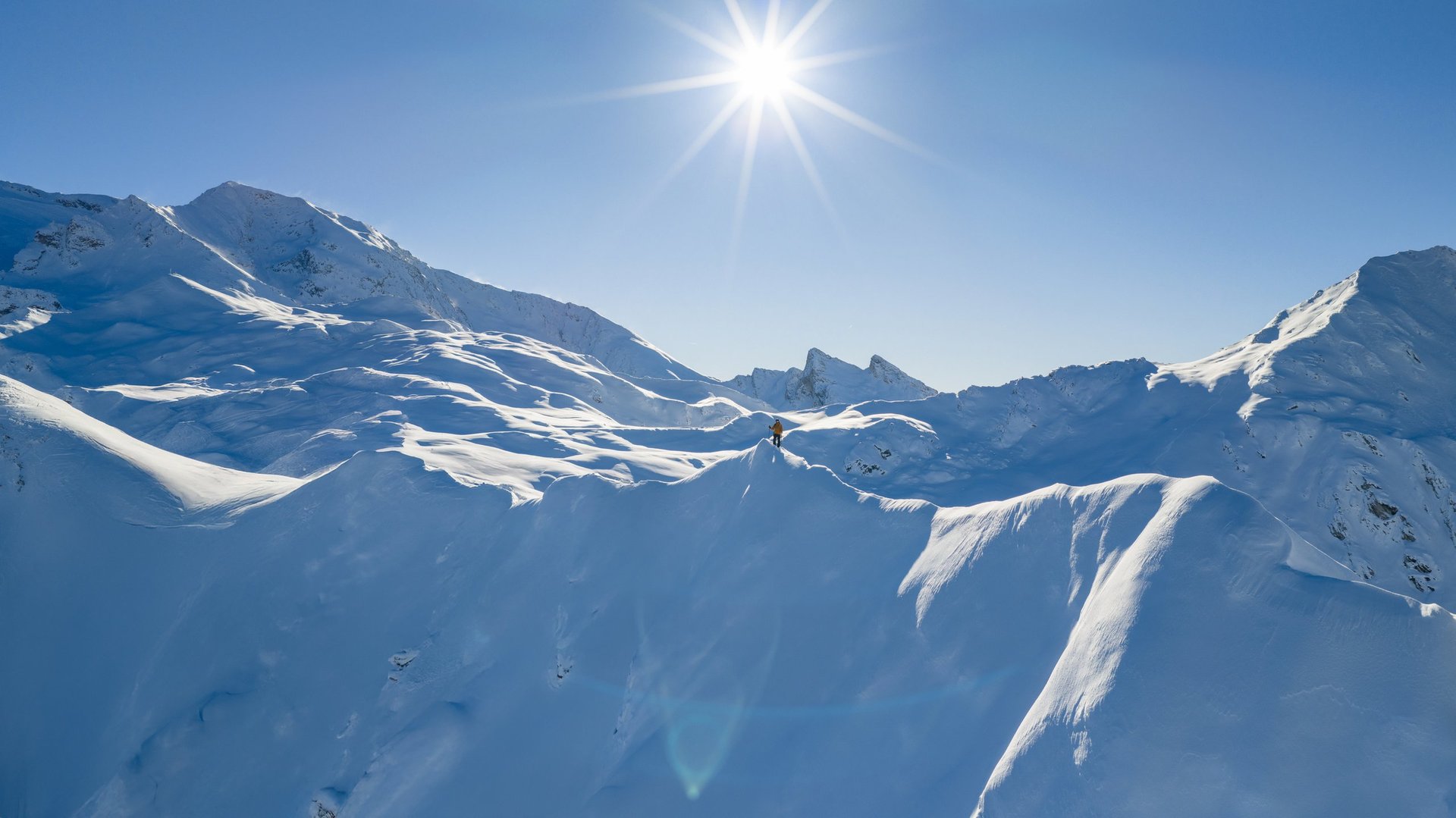 Panorama view of snow-covered high mountains in Alps with ski mountaineer