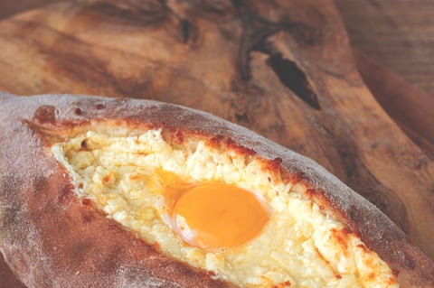 Freshly baked Adjarian khachapuri with beaten egg, traditional Georgian cheese bread