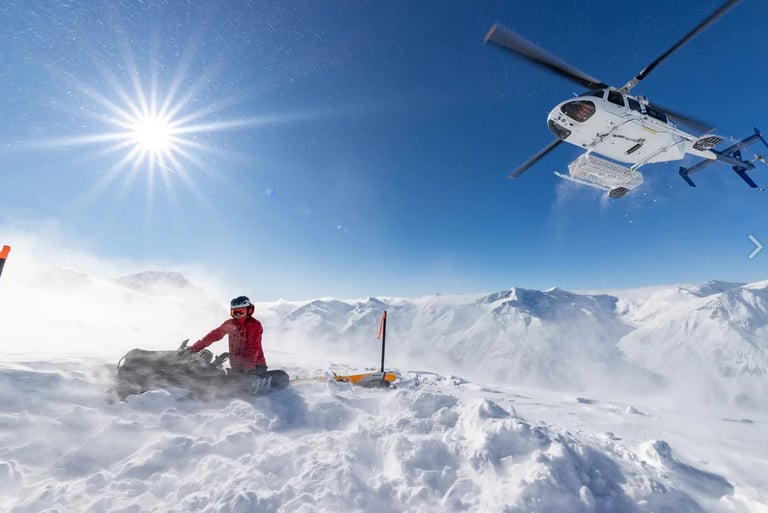 Helicopter rescue operation in snowy mountains with person in red jacket on snow-covered terrain under clear blue sky